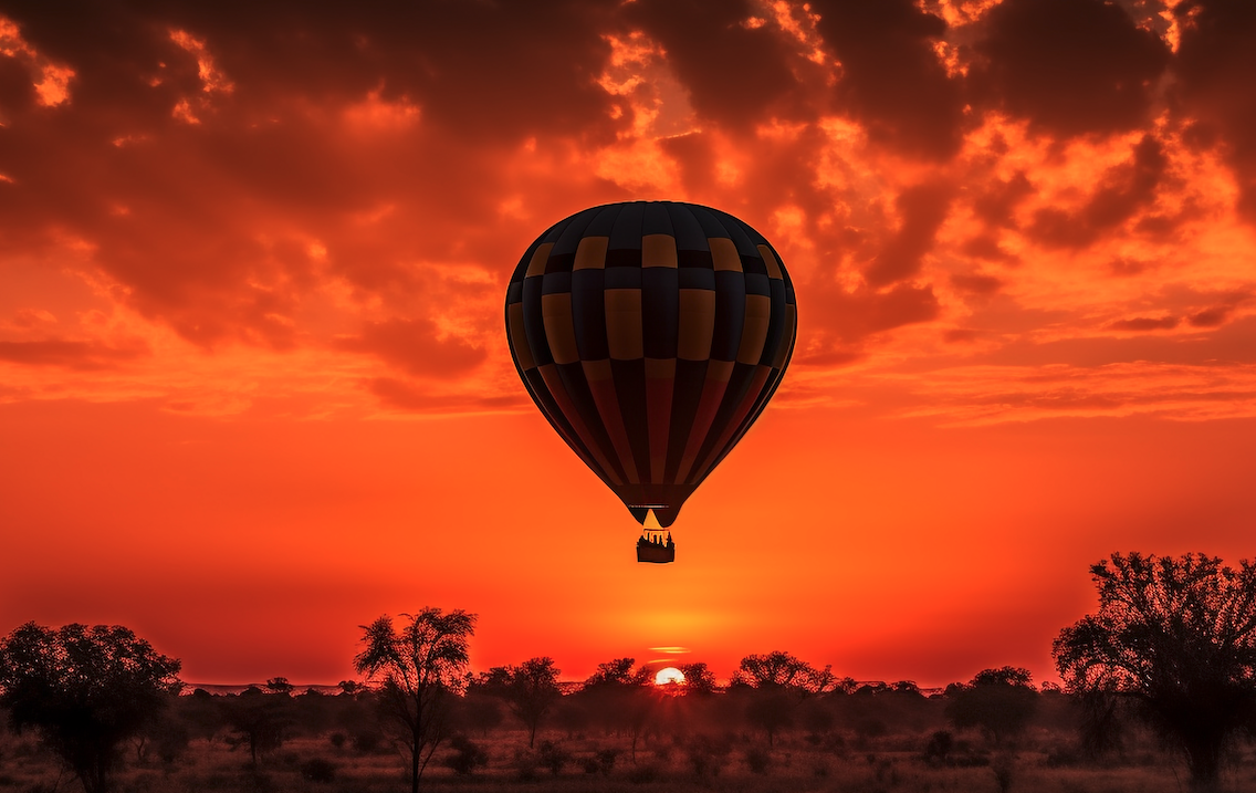 Hot air balloon floating over African savanna at sunset