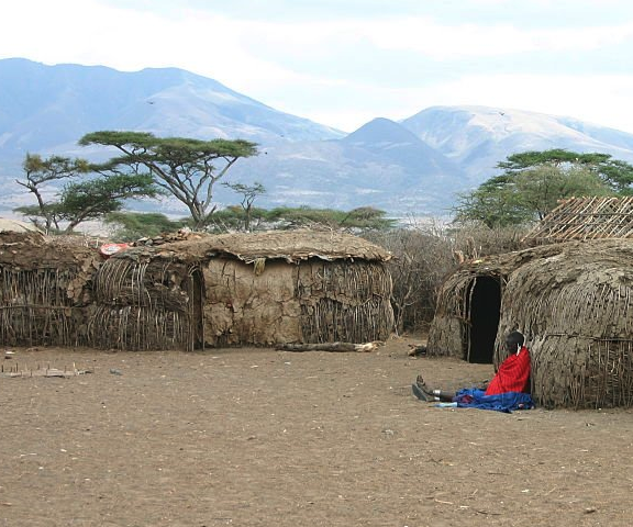 Traditional Maasai village with mud houses and person in red clothing